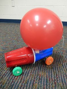 a red balloon sitting on top of a plastic barrel