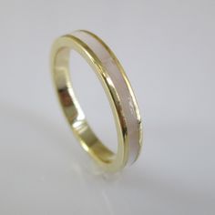 two tone gold wedding ring with white and yellow stripes on the outside, set against a plain background