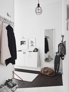 a white room with clothes hanging on the wall and an open door to another room