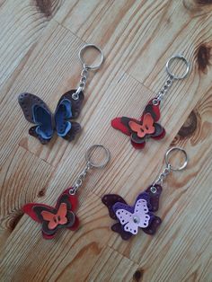 four butterfly shaped key chains sitting on top of a wooden table