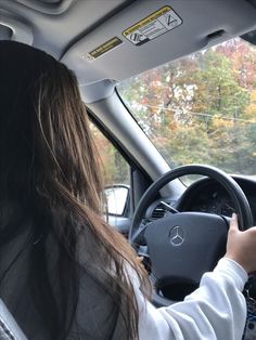 a woman driving a car with her hands on the steering wheel