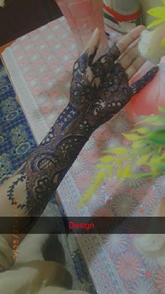 a woman's hand with henna on it and flowers in front of her