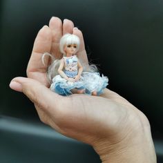 a hand holding a small doll in it's palm