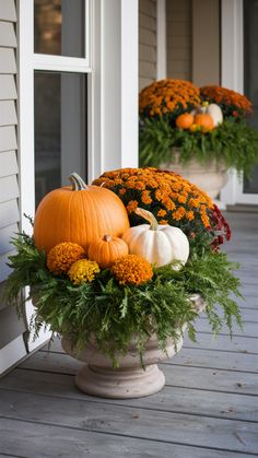 two pumpkins and flowers in a planter on the porch