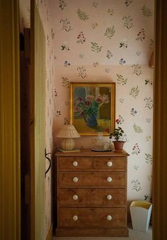 a dresser with flowers on the wall and a painting above it