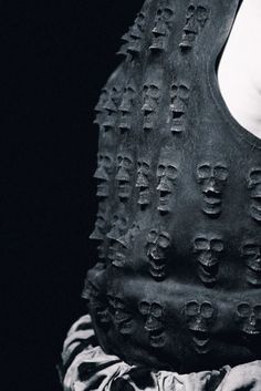 a black and white photo of a person wearing a vest with skulls on it's back