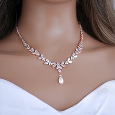 a woman wearing a necklace with pearls and leaves on the neck, in front of a mannequin