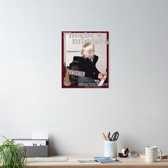 a poster hanging on the wall above a desk with a keyboard and coffee mugs