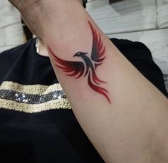 a person with a tattoo on their arm holding up a red and black bird in the air