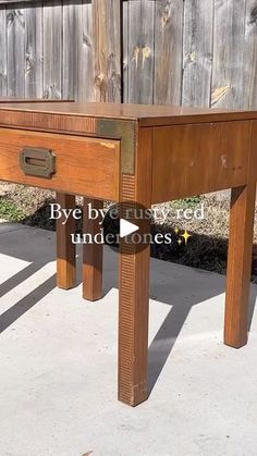 a wooden table sitting on top of a cement ground next to a fence with the words bye bye closed under it