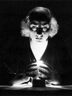 an old black and white photo of a woman holding a lit candle in her hands