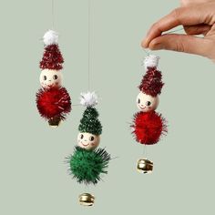 three christmas ornaments hanging from the ceiling with one being held by a person's hand