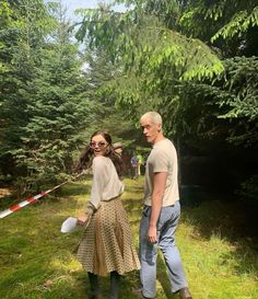 two people standing in the grass near trees