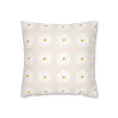 a white and yellow pillow with daisies on it