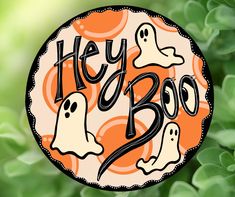 a sticker that says hey boo with ghost faces on it and green leaves in the background