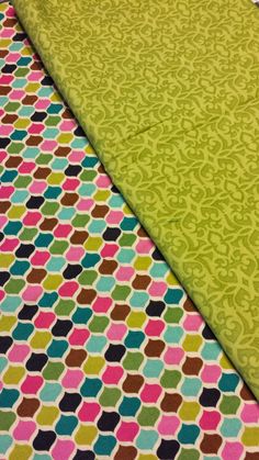 two pieces of fabric with different colors and patterns on the ground, one has a green background