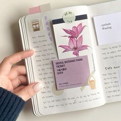 a person is holding an open book with flowers on it and the pages are pink