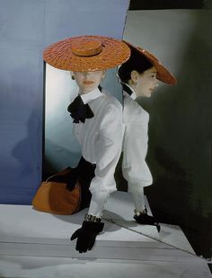 two mannequins dressed in white and black with hats on their heads, one holding a purse