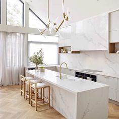 a kitchen with white marble counter tops and wooden flooring next to a large window