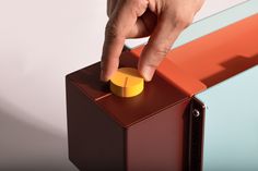 a hand pushing a button on top of a colorful object