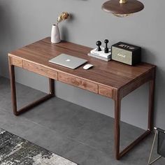 a desk with a laptop on it in front of a gray wall and two pictures