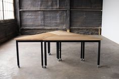 a wooden table with four metal legs in an empty room