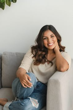 a woman sitting on a couch smiling at the camera