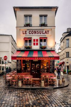 a small restaurant with tables and chairs in front of it on a cobblestone street