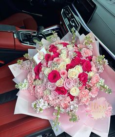 a bouquet of pink and white flowers sitting on top of a red car dash board