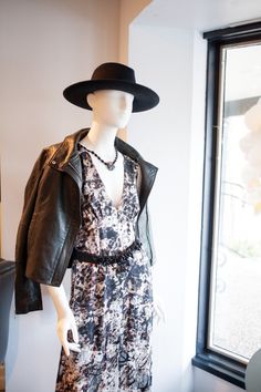 a mannequin wearing a black leather jacket and hat in front of a window