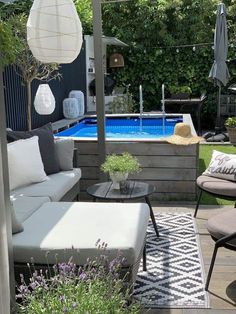 an outdoor living area with couches, tables and umbrellas next to a swimming pool