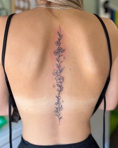 the back of a woman's body with flowers on her left shoulder and lower back