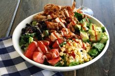 a white bowl filled with salad on top of a blue and white checkered table cloth