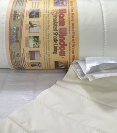 a roll of white fabric sitting on top of a bed next to a pillow case