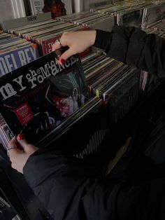 a person holding up a record in front of a rack of cds