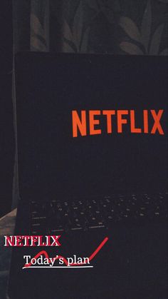 a black laptop computer sitting on top of a table next to a window with the netflix logo