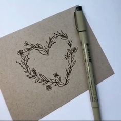 a pen is sitting next to a piece of paper with a heart drawn on it