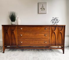 a large wooden dresser sitting on top of a white carpeted floor next to a potted plant