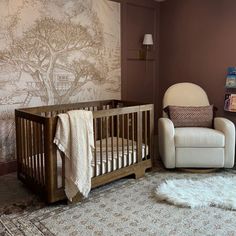 a baby's room with a rocking chair, crib and wallpaper on the walls