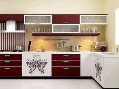 a kitchen with red cabinets and white counter tops on the wall is decorated with decorative decals