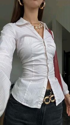 a woman in white shirt and black pants with gold jewelry on her neck posing for the camera