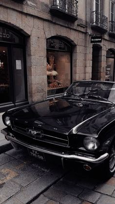 an old black mustang parked on the side of the street