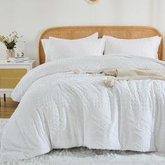 a bed with white comforter and pillows in a bedroom