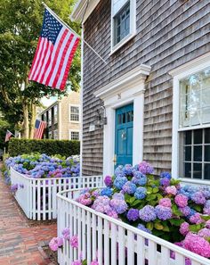 the american flag is flying over hydrants in front of a house with blue doors and shutters