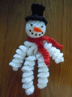 a snowman made out of yarn sitting on top of a wooden table