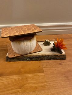 a piece of cheese sitting on top of a cutting board next to an orange flower