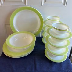 a stack of green and white dishes sitting on top of a blue table cloth