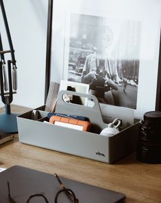 an office desk with a pen, glasses and other items on it next to a framed photograph