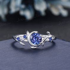 a ring with blue sapphire stones on it and leaves around the band, sitting on top of a book