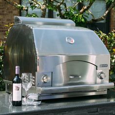 a stainless steel toaster sitting on top of a counter next to a bottle of wine